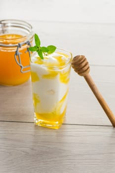 prepared homemade yogurt with natural honey in a glass on a light wooden table.