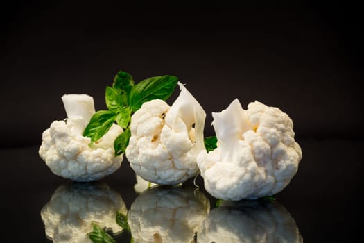 slices of raw small raw cauliflower isolated on black background