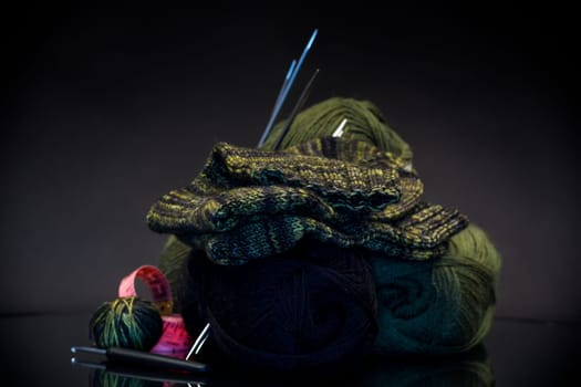 wool yarn, knitting needles and other tools for hand knitting, isolated on a black background.
