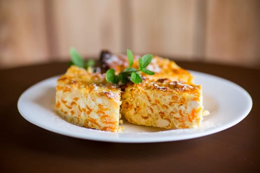 Cooked cottage cheese casserole with pieces of pumpkin inside, on a wooden table.