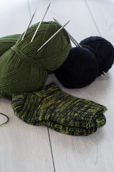 wool yarn, knitting needles and other tools for hand knitting, on a wooden table.