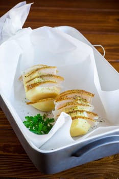 Raw potatoes stuffed with lard and spices, prepared for baking in baking paper.