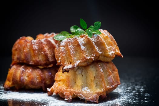 cooked sweet honey muffins in powdered sugar isolated on black background