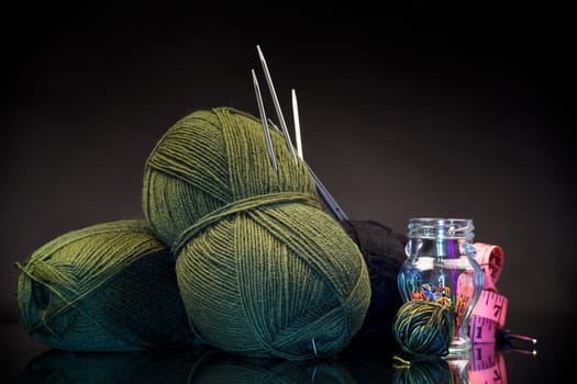 wool yarn, knitting needles and other tools for hand knitting, isolated on a black background.