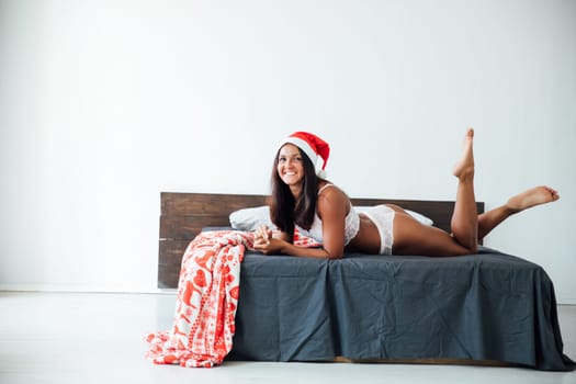 woman in hat in bedroom on bed christmas gifts