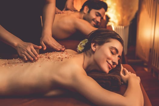 Couple customer having exfoliation treatment in luxury spa salon with warmth candle light ambient. Salt scrub beauty treatment in Health spa body scrub. Quiescent