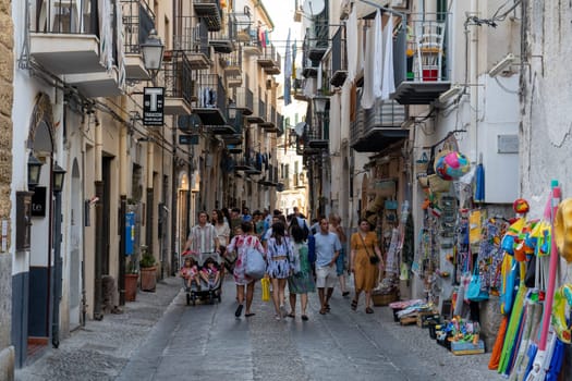 Cefalu, Sicily - July 21, 2023: People in a small alley with shops in the historic city center.