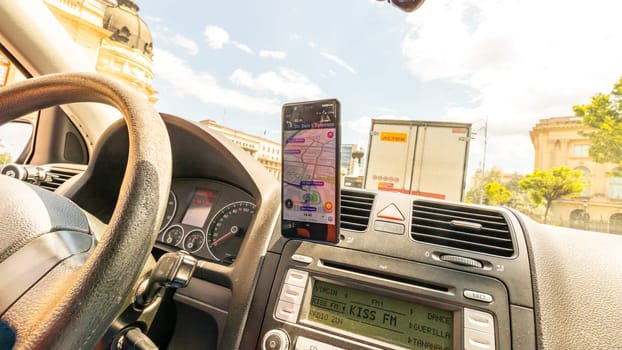 Smartphone showing Waze maps to show the way thru the city. Driver using Waze maps