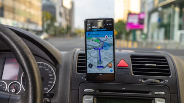 Smartphone showing Waze maps to show the way thru the city. Driver using Waze maps