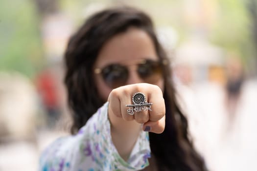 Young Indian woman punching towards camera with face hidden with a ring saying musafir meaning traveller in India