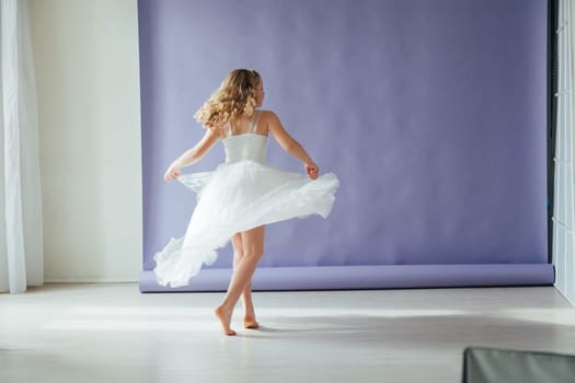 Girl of 10 years in a dress dances to the music alone in the room