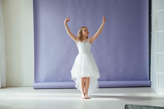 Girl of 10 years in a dress dances to the music alone in the room