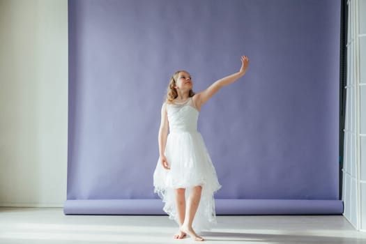 Girl of 10 years in a dress dances to the music alone in the room