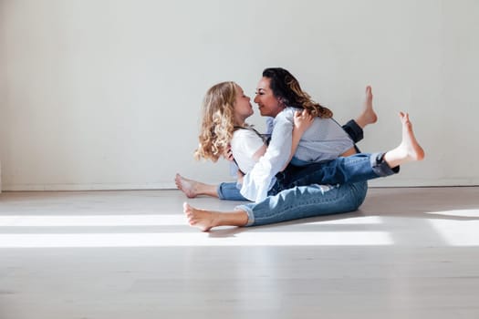 Mom and daughter in denim play in white family love