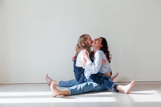 Mom and daughter in denim play in white family love