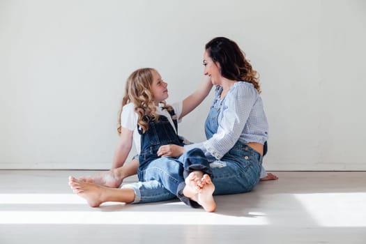 Mom and daughter in denim play in white family love