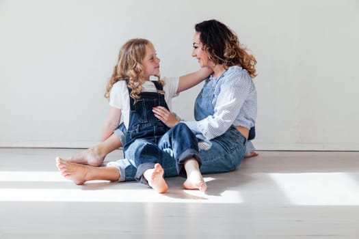 Mom and daughter in denim play in white family love