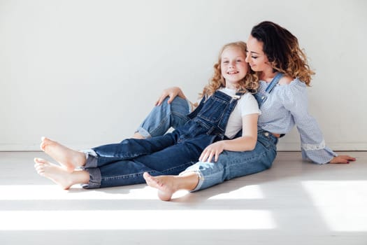 Mom and daughter in denim play in white family love