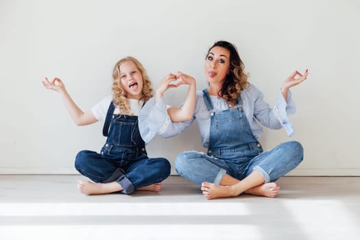Mom and daughter in denim play in white family love