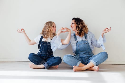 Mom and daughter in denim play in white family love