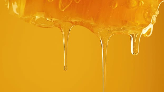 Honey dripping from honeycombs extreme macro.Natural beeswax cells, gold nectar. Organic liquid dessert pouring on yellow warm background. High quality
