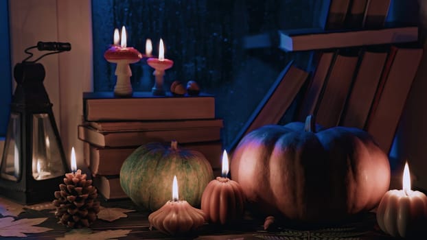 Stack of old paper books on windowsill in soft candles glow light. Cozy ambience of fall. Literature promotions or tranquil visual storytelling. Rainy autumn weather, vintage styled room. Asmr.