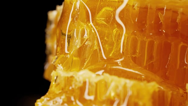 Raw honeycombs with pouring pure golden honey elixir. Amazing tasty flow. Macro texture, structure of flower nectar. Sweet visuals, stunning details. High quality