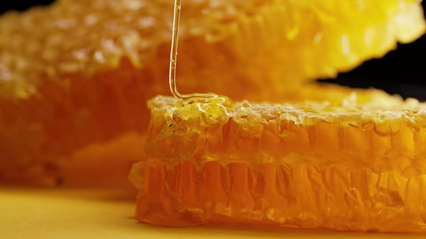 Raw honeycombs with pouring pure golden honey elixir. Amazing tasty flow. Macro texture, structure of flower nectar. Sweet visuals, stunning details. High quality