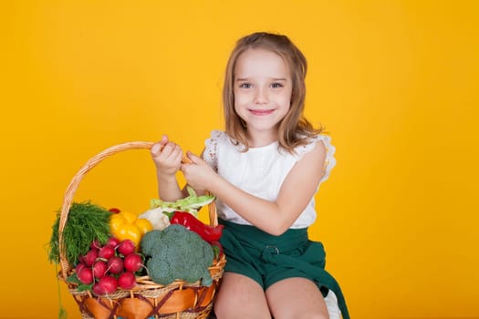 Little girl holds a basket of ripe vegetables radish pepper broccoli