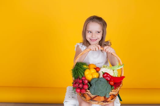 Little girl holds a basket of ripe vegetables radish pepper broccoli