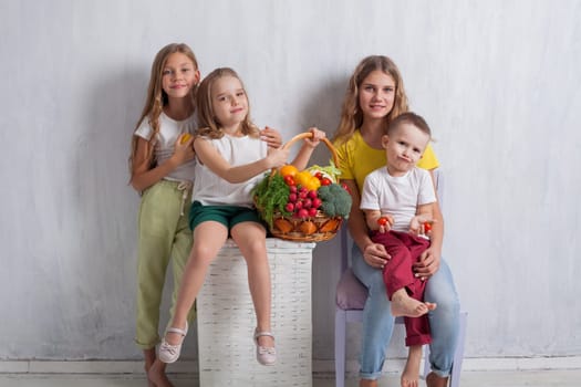 kids boy and three girls with a basket of ripe vegetables and fruits