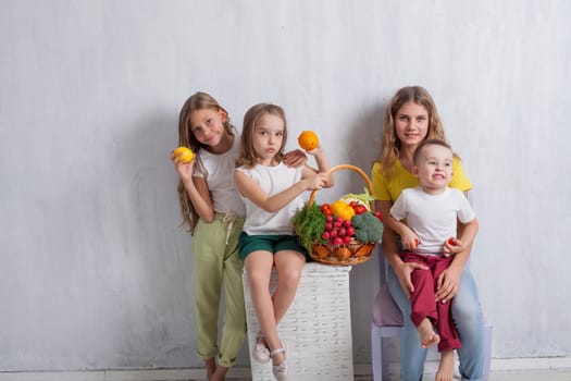 kids boy and three girls with a basket of ripe vegetables and fruits