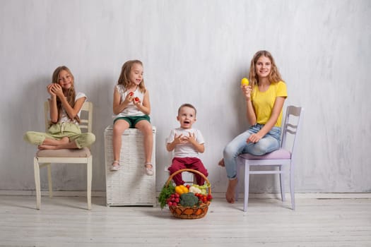 kids boy and three girls with a basket of ripe vegetables and fruits