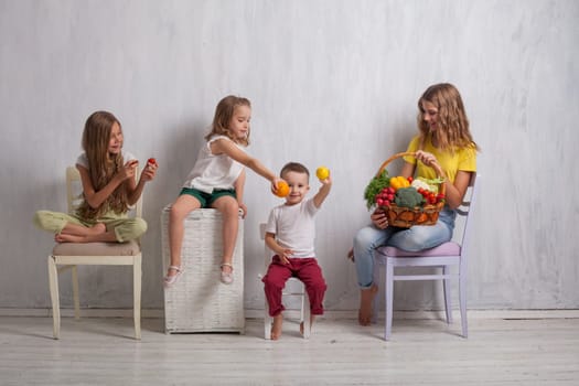 kids boy and three girls with a basket of ripe vegetables and fruits