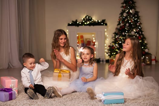 Children cover gifts at the Christmas tree lights garlands