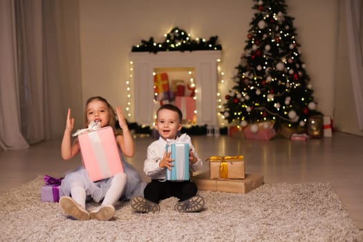 Children cover gifts at the Christmas tree lights garlands