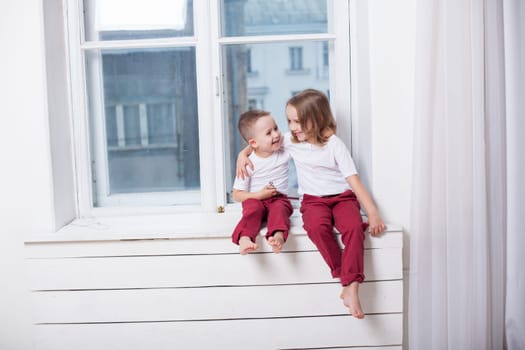 little boy and girl sitting by the window without parents