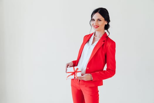 business woman brunette in a red business suit with a gift