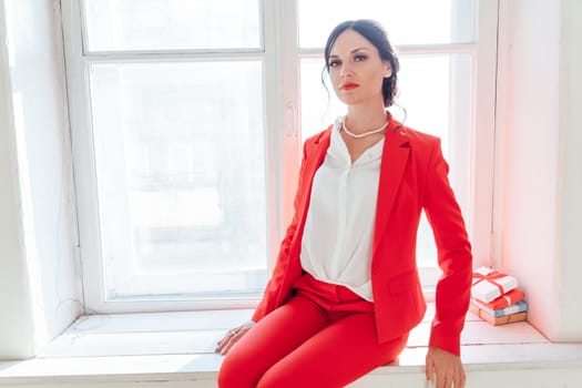 business woman brunette in a red business suit with a gift
