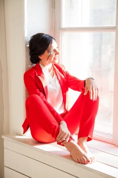 business woman brunette in a red business suit by the window