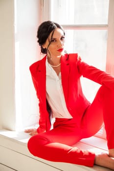 business woman brunette in a red business suit by the window