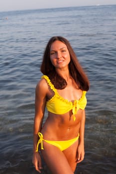 woman with long hair in yellow swimsuit on sea beach walk