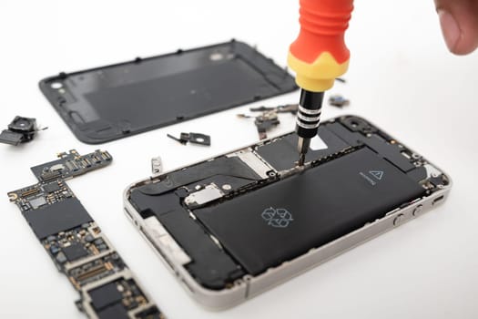 Technician repairing inside the smartphone motherboard with tools for recovery, The man repair by tightening nut from mobile phone with a screwdriver to fix problem