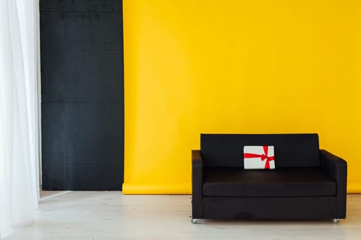 black office sofa with red gifts in the interior of the room with a yellow background