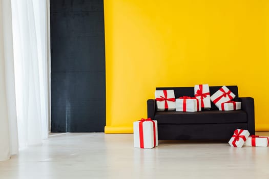 black office sofa with red gifts in the interior of the room with a yellow background