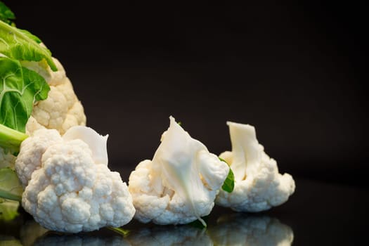 slices of raw small raw cauliflower isolated on black background