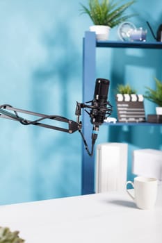Professional microphone for podcast sound recording at empty blogger workspace. Black mic equipment for digital content creating in modern vlogger home studio with no people