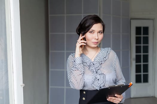 Asian woman talks on smartphone in the office