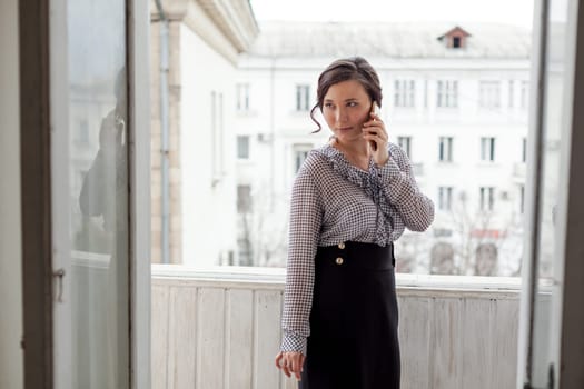 Asian woman talks on smartphone in the office