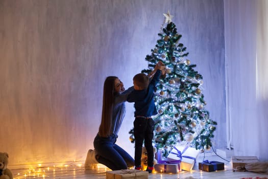 Mom and son on New Year's Eve at Christmas tree gifts lights garlands